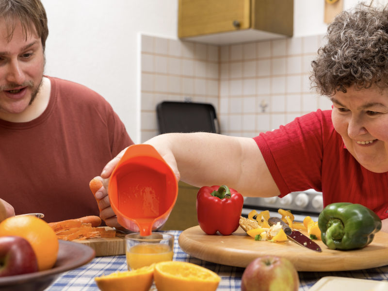 woman pouring squeezed orange juice into a cup